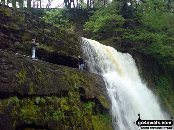 Two guys taking a chance at Sgwd yr Elra Waterfall, Afon Mellte in the background