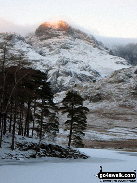 The last rays on sunshine on The Langdale Pikes across a frozen Blea Tarn (Langdale)