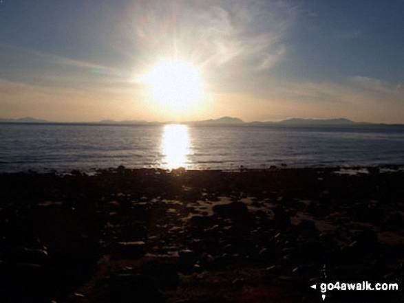 The sun setting behind the hills of The Lleyn Peninsula across Tremadog Bay from Llandanwg